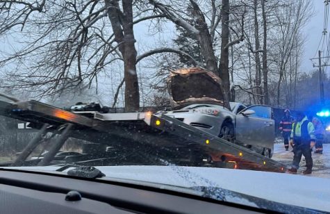 Olivias car is loaded onto a tow truck after hitting a tree during a snowstorm. 