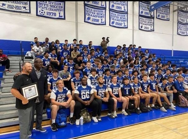 Here the Leominster High School Football Team poses for a team picture in their jerseys in the highschool gym. Head Coach Devin Gates is on the far left with New England Patriots Hall of Famer Andre Tippet. Coach Gates was awarded the Coach of the Week by the New England Patriots. 

The boys are hopeful and excited for their annual game against the neighboring opponent and plan to bring all the heat as they are going to be playing in their last game together forever, some who have been playing together since they were small children. 
